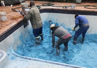 Guys working on the blue concrete and plaster mixture for the pools interior.