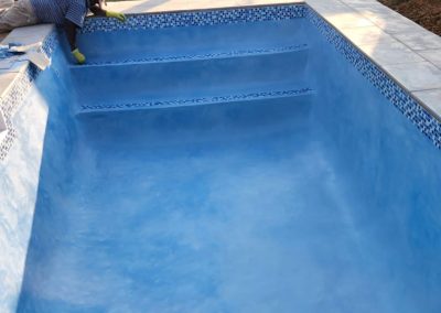 Small concrete pool project almost finished with blue interior.